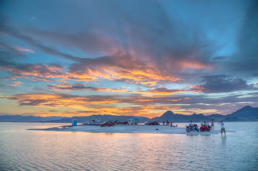 Bonneville salt flats at sunset with motor vehicles on an island.