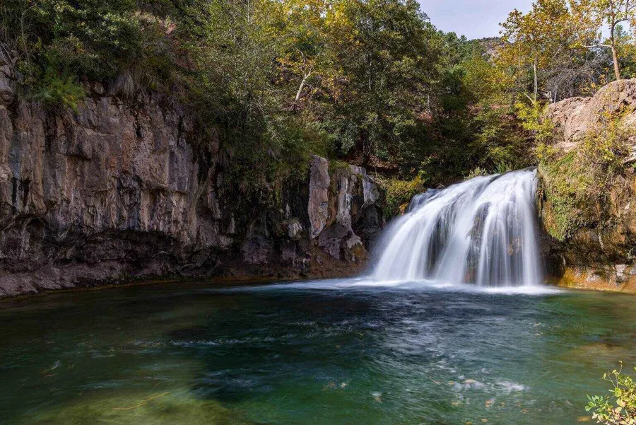 A scenic waterfall surrounded by greenery at Coconino National Forest near the city of Sedona, Arizona.