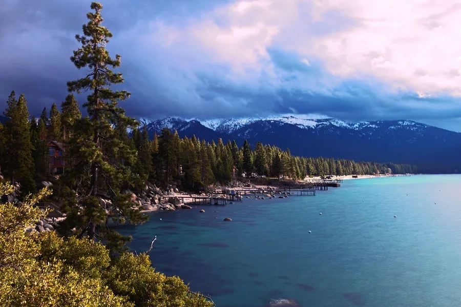 Lake Tahoe in California surrounded by forests with mountain ranges in the background.