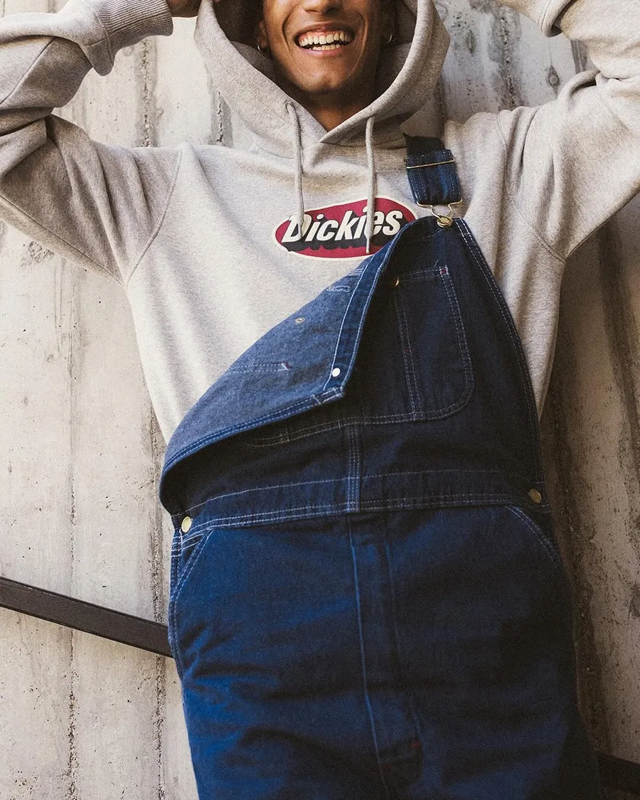 A man smiling wearing Dickies denim overalls.