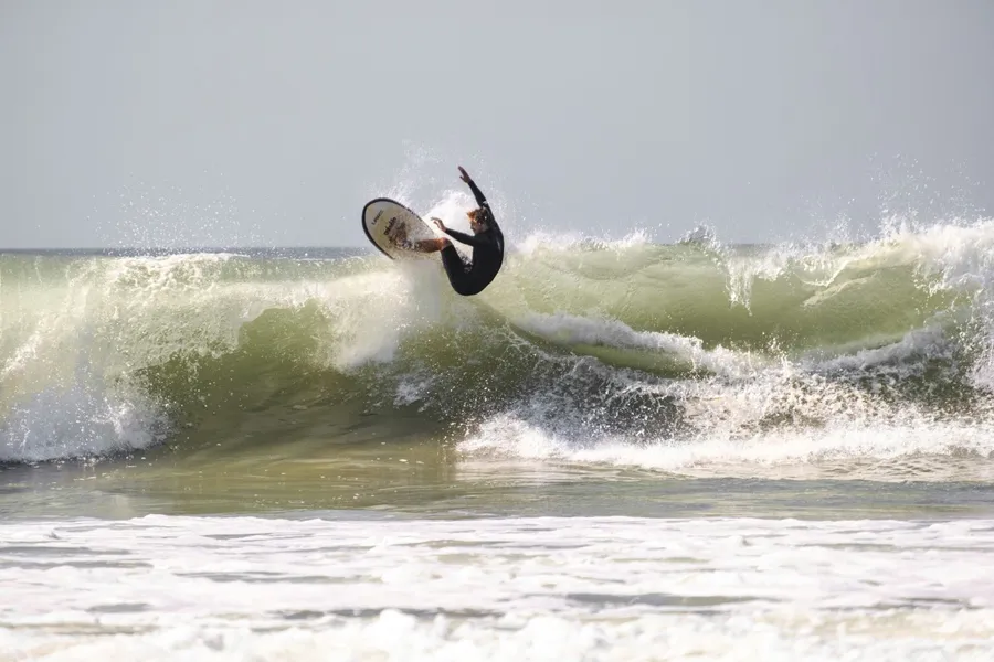 A surfer in a wetsuit on his surfboard riding a wave in the sea at Ventura Beach, California