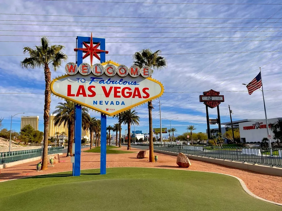 The Welcome to Las Vegas sign with palm trees behind it and the American flag on the right.