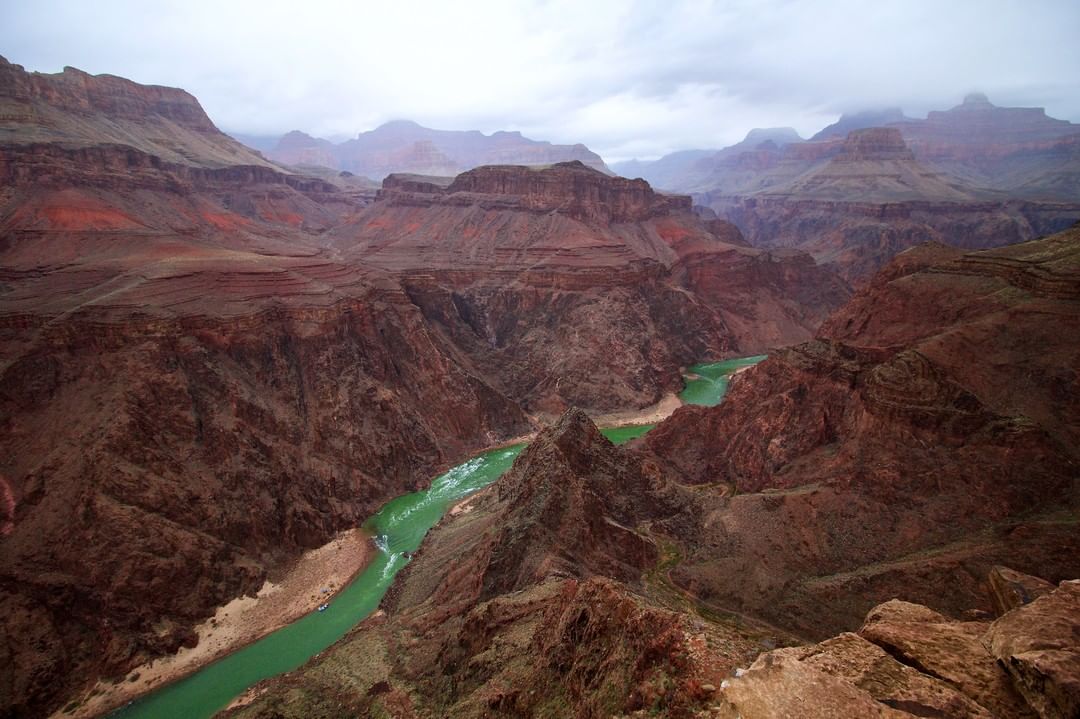 The green Colorado River passing between two giant red canyons in Utah.