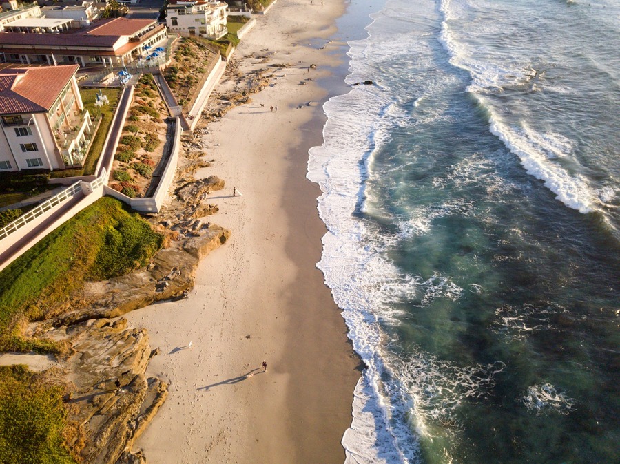 Aerial view of a wavy sea at the beach in La Jolla next to houses in San Diego, California.