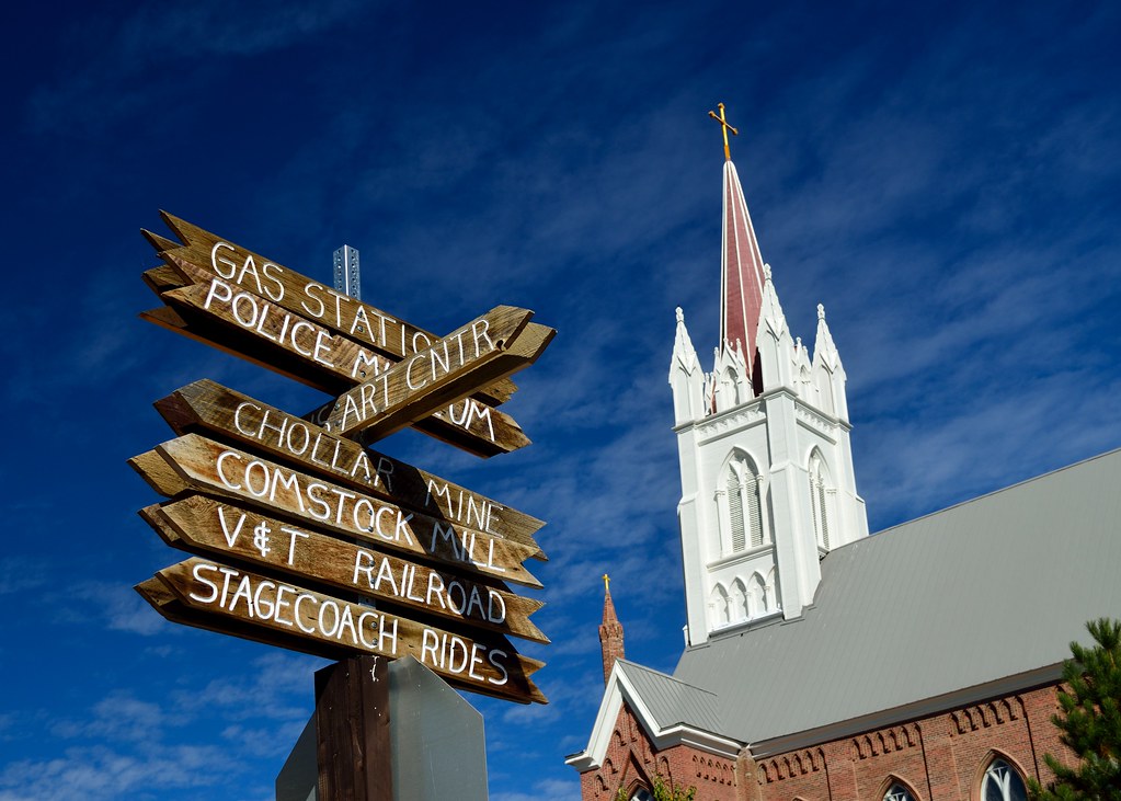 A picture of directional signs in Virginia City with Saint Mary In the Mountains in the background.